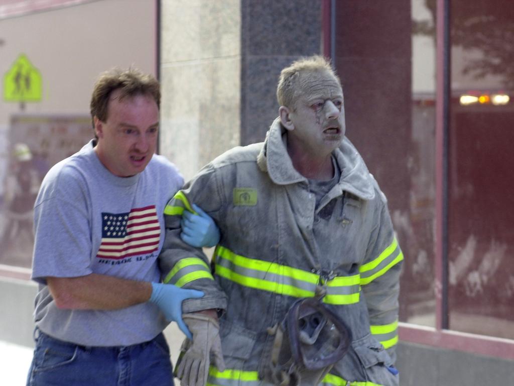 A firefighter covered with ash is helped by a civilian after the World Trade Centre collapses in a terrorist attack. Picture: Thomas Monaster/NY Daily News Archive via Getty Images