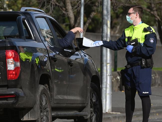 Police officers pull a car over for a licence and permit check in Melbourne on August 11, 2020, during a strict stage four lockdown of the city due to a COVID-19 coronavirus outbreak. - Victoria state reported 19 deaths from coronavirus on August 11, making it the country's equal deadliest day of the pandemic despite a fall in new case numbers. (Photo by William WEST / AFP)