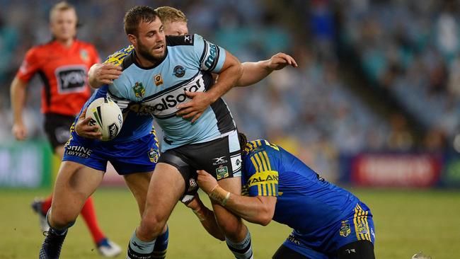 Sharks forward Wade Graham looks to offload the ball in a tackle.