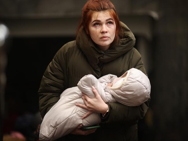 A woman carrying a baby races to board a train to Poland in Lviv, Ukraine. Picture: Getty Images