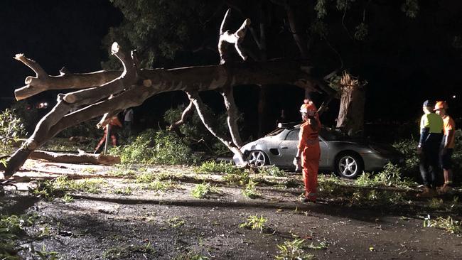 The SES work to move the tree branches off the Porsche and road. Picture: David Meddows