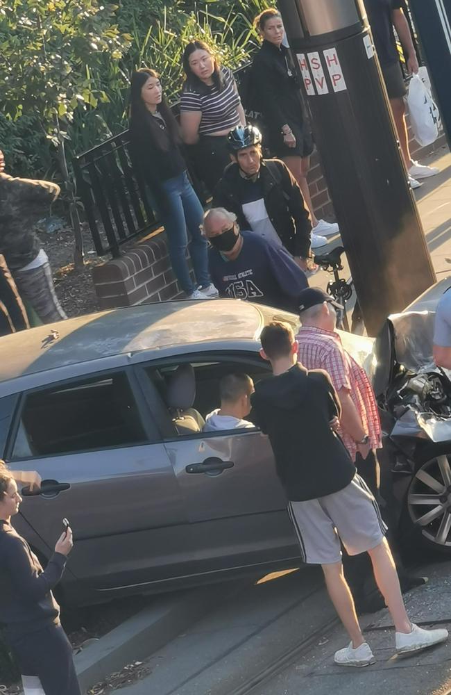 Concerned onlookers surround the man’s car following the collision. He has since been taken to hospital in a stable condition.