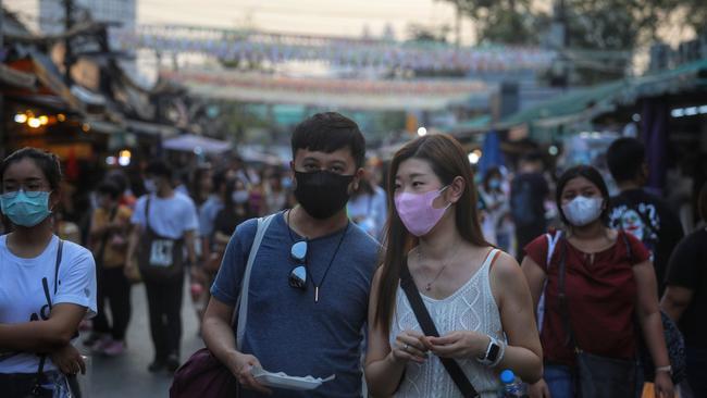 People stroll through Chatuchak weekend market in Bangkok, Thailand, wearing masks. Picture: AFP