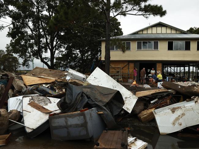 Geoff and Jennie Youll enjoy a drink around a campfire with family and friends after cleaning out their property in Woodburn. Picture: Jonathan Ng