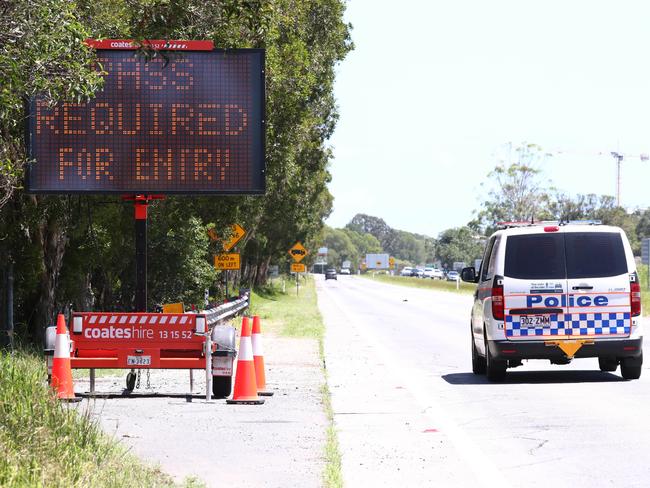 Motorists drive past signs at the Queensland and New South Wales border on The Gold Coast Highway.Photograph : Jason O'Brien
