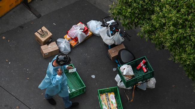 A delivery worker bringing food to residents next to a checkpoint on a closed street during a Covid-19 coronavirus lockdown in the Jing'an district in Shanghai. Picture: AFP