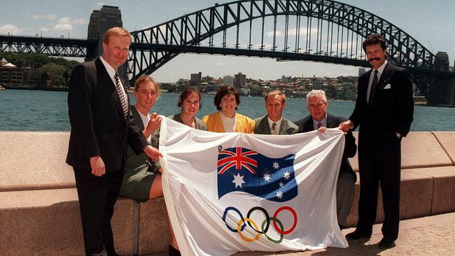 Australian Olympic Committee president John Coates with unnamed AOC and Visa officials holding flag in 1995 cementing sponsorship deal, Visa to send 90 athletes to Atlanta 1996 Olympic Games.