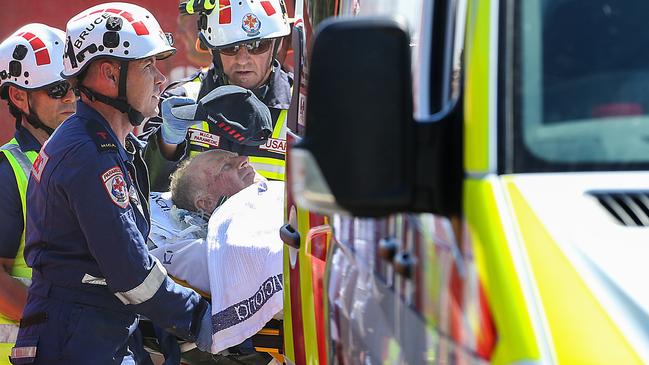 One of the two rescued men is ferried to a waiting ambulance. Picture: Ian Currie