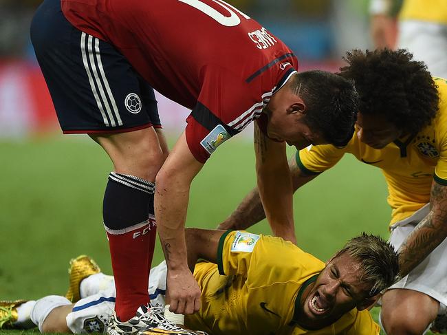 Brazil's forward Neymar (C) is helped by Brazil's defender Marcelo (R) and Colombia's midfielder James Rodriguez (L) as he lies on the pitch after being injured during the quarter-final football match between Brazil and Colombia at the Castelao Stadium in Fortaleza during the 2014 FIFA World Cup on July 4, 2014. AFP PHOTO / EITAN ABRAMOVICH