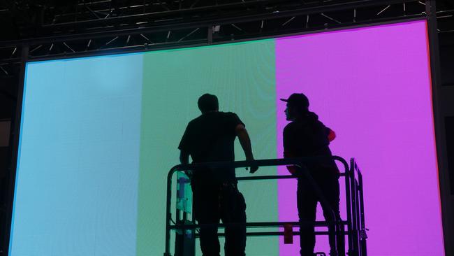 Workers install a monitor in preparation for the International CES gadget. Credit: AP