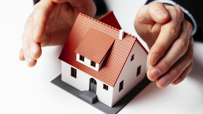 MONEYSAVER Home insurance concept. Man holding hands above miniature home
