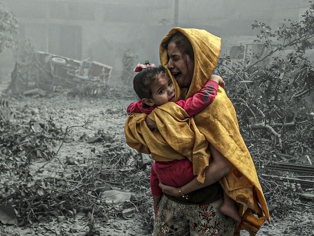 A woman holding a girl reacts after Israeli air strikes hit Ridwan neighbourhood of Gaza City in October. Picture: Ali Jadallah/Anadolu