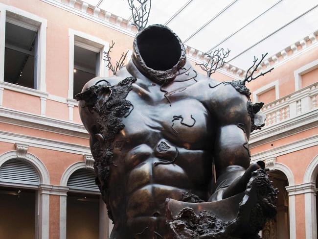 People look at "Demon with Bowl" by British artist Damien Hirst during the press presentation of his exhibition "Treasures from the Wreck of the Unbelievable" at the Pinault Collection in Punta della Dogana and Palazzo Grassi in Venice on April 6, 2017. / AFP PHOTO / MIGUEL MEDINA / RESTRICTED TO EDITORIAL USE - MANDATORY MENTION OF THE ARTIST UPON PUBLICATION - TO ILLUSTRATE THE EVENT AS SPECIFIED IN THE CAPTION