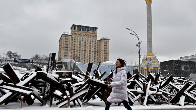 A young woman walks past anti-tank steel hedgehogs covered with snow along Independence Square in the Ukrainian capital Kyiv. Picture: AFP