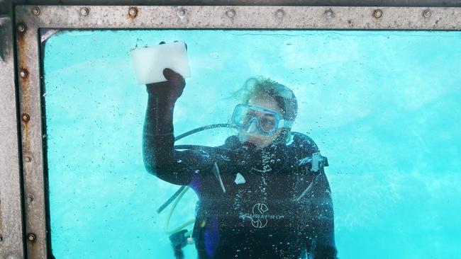 Sunlover dive instructor Iris Poachinger cleans the glass panels on the semi submersible boat. Picture: Brendan Radke