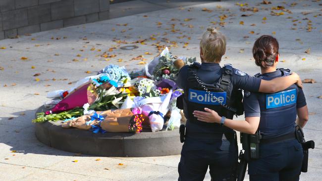 Two police women pay their respects. The Police memorial with flowers to remember the four police killed on the Eastern freeway. Saturday, April 25, 2020. Picture: David Crosling