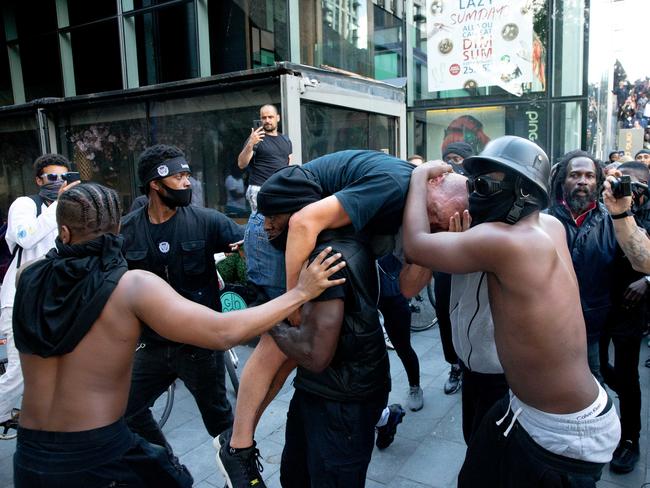 An injured far-right protester is carried to safety by Black Lives Matter supporters. Picture: Getty Images