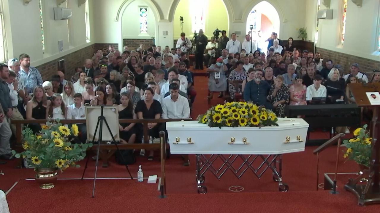 The white casket was covered in sunflowers.