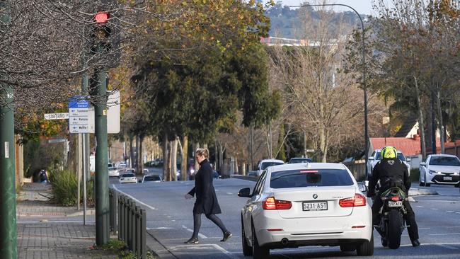 Pedestrians cross at the corner of Portrush Rd and Stafford Grove in front of Loreto College in Marryatville. The crossing was supposed to be cleared of vegetation obscuring the lights. Picture: Brenton Edwards