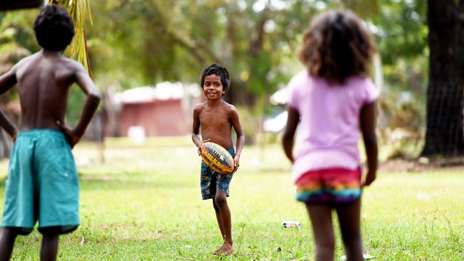 Xavier, 6, plays football with other kids in his backyard.