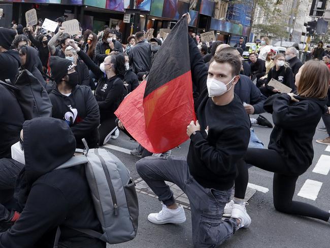 Protesters stop to go on one knee during a march in Sydney, Saturday, June 6, 2020, to support the cause of U.S. protests over the death of George Floyd. Black Lives Matter protests across Australia proceeded mostly peacefully as thousands of demonstrators in state capitals honored the memory of George Floyd and protested the deaths of indigenous Australians in custody. (AP Photo/Rick Rycroft)