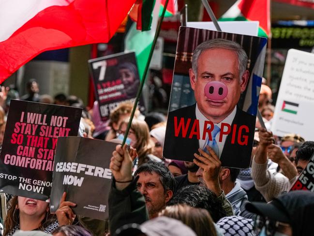 MELBOURNE, AUSTRALIA - OCTOBER 06: A general view as Pro-Palestine protesters waving Palestine flags as a protester holds a placard of Benjamin Netanyahu on October 06, 2024 in Melbourne, Australia. Organizers of pro-Palestine protests in Sydney are set to proceed with a rally on Sunday, October 6, despite legal attempts by police to prohibit the gatherings due to safety concerns related to anticipated crowd sizes and potential disruptions. The following day, a vigil is scheduled to honor victims of violence in Gaza, coinciding with the one-year anniversary of the Hamas attacks, which has drawn criticism from government officials who deem the timing "extremely provocative". Protesters also planned to gather for similar events in Melbourne. (Photo by Asanka Ratnayake/Getty Images)