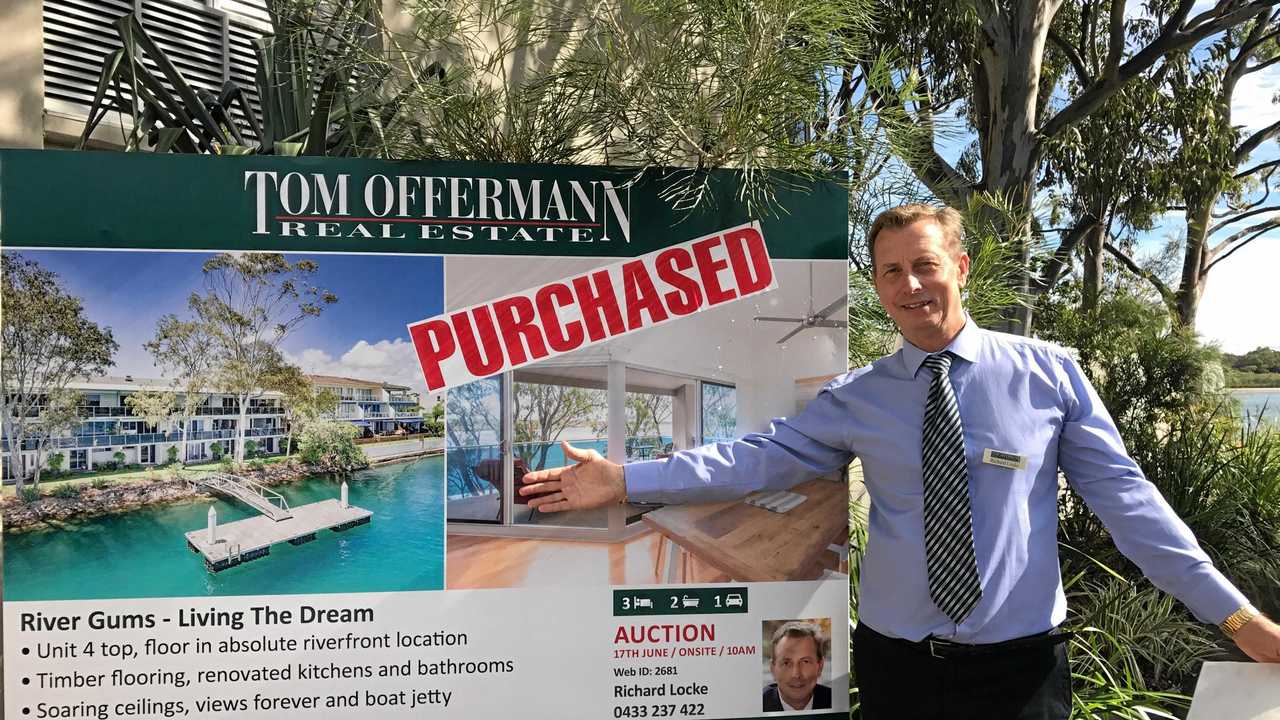 Tom Offermann Real Estate's Richard Locke puts the PURCHASED sign on the riverfront property after auction. Picture: Contributed