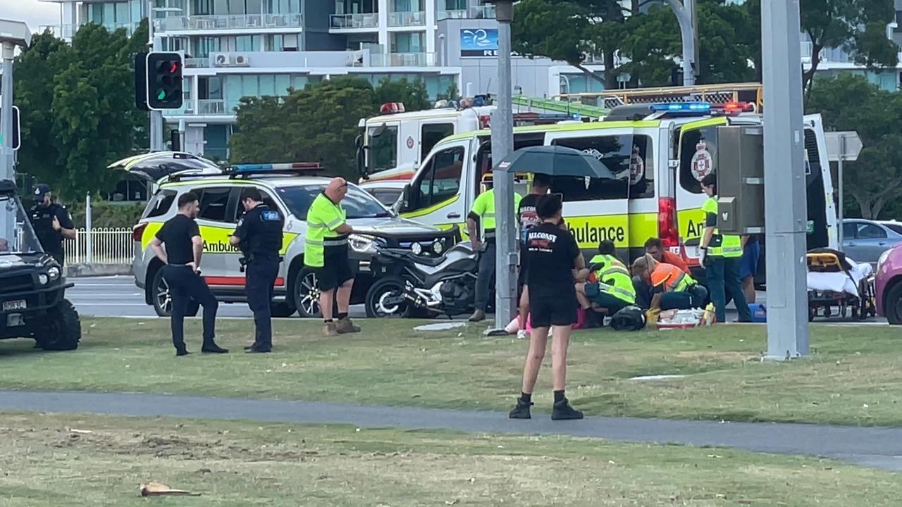 A man is being treated by paramedics following a car and motorbike crash on the Gold Coast Highway in Southport. Photo: Charlton Hart