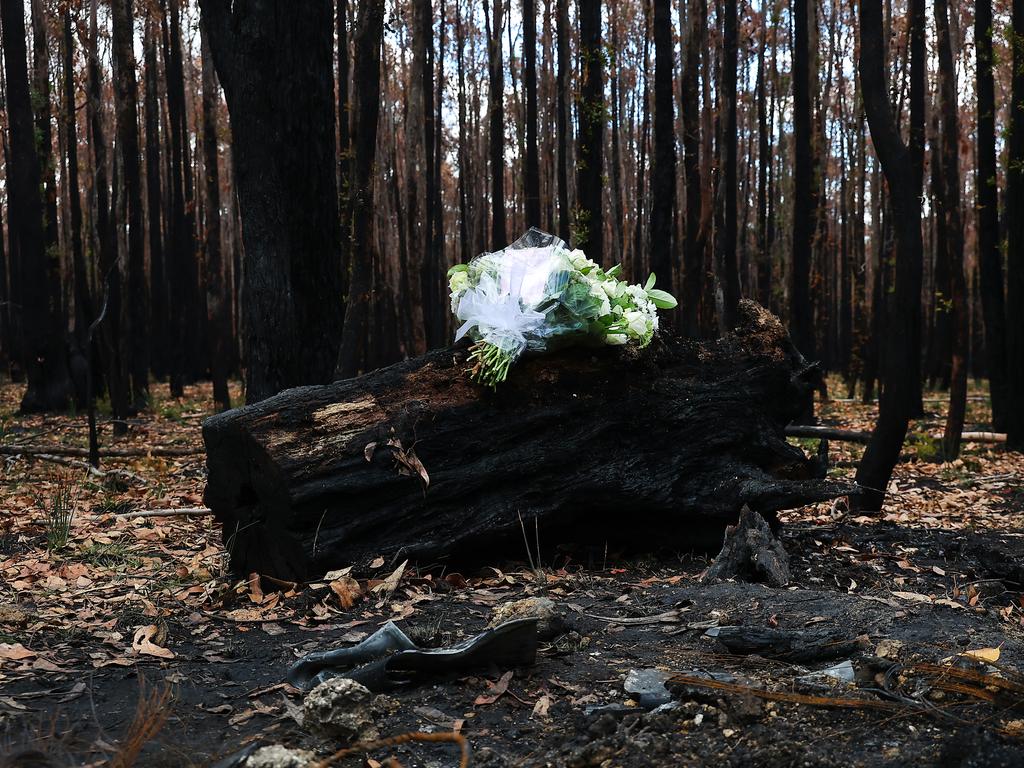 Flowers lay on top of a burnt log where Hannah McGuire’s body was found. Picture: Ian Currie