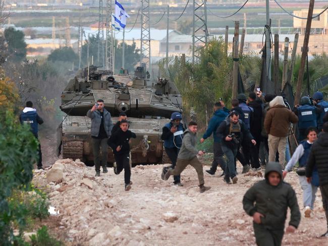 Palestinian children and journalists disperse as Israeli tanks enter the Jenin camp for Palestinian refugees in the occupied West Bank, on February 23, 2025. Israel on February 23 said troops would stay in West Bank refugee camps for the coming year, announcing expanded military operations including tank deployments, after the displacement of tens of thousands of Palestinians. (Photo by Jaafar ASHTIYEH / AFP)