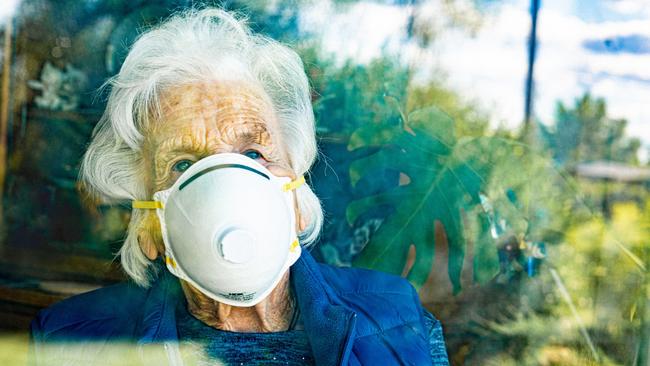 Distraught Elderly Senior Caucasian Woman Looking Out the Window Feeling Loneliness Wearing an n95 Protective Face Mask To Prevent the Spread of Covid. aged care generic