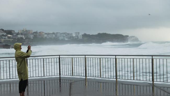 A lone walker at Bronte Beach on Friday morning takes a picture of the huge swells. Picture: John Grainger