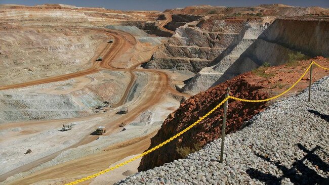 Visitors cast shadows as they look out over part of the main pit of a copper and gold mine in Western Australia. Picture: Will Burgess / Bloomberg News