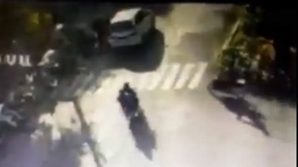 Still from surveillance footage showing a motorcyclist (left) driving into the grounds of a church and detonating a bomb.