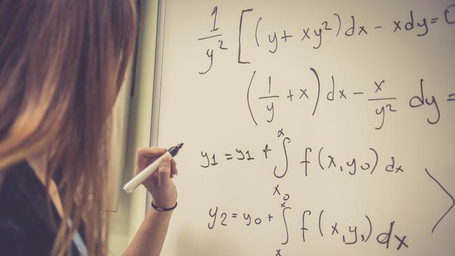 CAREERS: Young female student, teacher, with long hair doing math at the whiteboard, Istanbul, Turkey. Rear view, copy space. Nikon D800, full frame, XXXL.