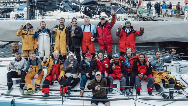 Sydney businessman Geoff Hill (middle row in red cap), celebrates with his crew on Antipodes and his daughter Natasha Parker (middle row wearing a beanie), who was on her first Sydney Hobart in the 2022 race. Picture: Bram Vanspengen