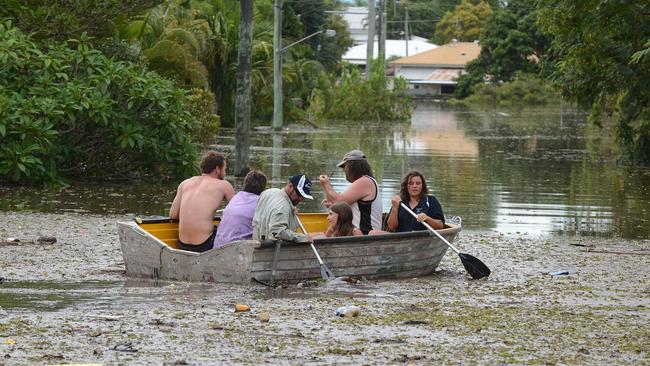 People in a boat negotiate flood water and debris in Bundaberg, Queensland, Monday, Jan. 28, 2013. Picture: AAP/Dan Peled