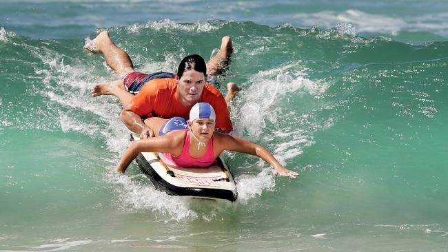 Nick Marshall assists Matilda Adams, 11, to make it to shore. Pic: Luke Marsden.