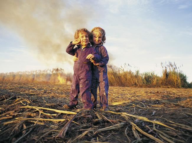 A Portrait of Australia: The best stories from 30 years of Australian Geographic. In their coveralls and work boots, Paul and Hayley Denman play next to a paddock of smouldering cane that their father, contract harvester Geoff, and uncle Stuart will harvest the following morning. They’re too young to appreciate the economic importance of the sugar industry, but there’s a good chance that, like many Mackay youngsters, they’ll work in it when they’re older. Photo by Paul Nevin
