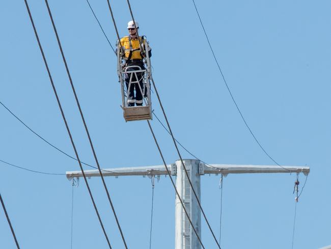 Is this Melbourne most dangerous job? working with 100 000 Volts at over 50 meters a worker from Zinfra works on the newly moved power lines along side the new West Gate Tunnel. He uses a hand propelled platform suspended on the wires themselves, near Yarravile.  Picture: Jason Edwards