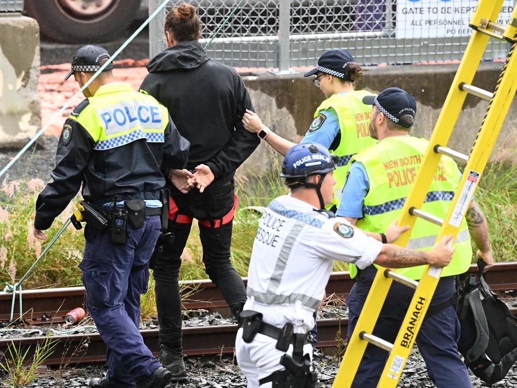 A protester is arrested after suspending himself on rail lines. Picture: Jeremy Piper