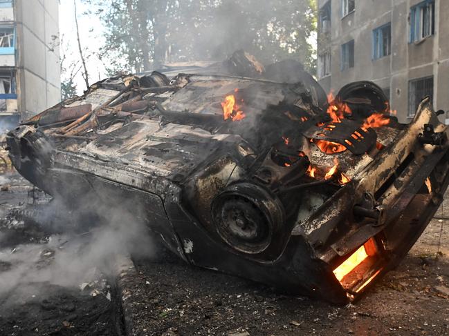 A burnt-out car is seen in the courtyard of a damaged residential building following a missile attack in Kharkiv on August 30, 2024. Russian strikes killed at least six people in the eastern Ukrainian city of Kharkiv, including a 14-year-old girl at a playground, and wounded dozens more, officials said on August 30, 2024. (Photo by SERGEY BOBOK / AFP)