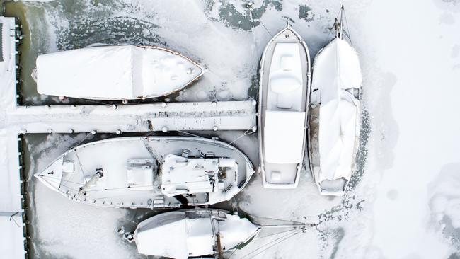 Picture taken with a drone shows snow-covered sailing ships mooring at the boatyard harbour of Kirchdorf on the Baltic Sea island of Poel, northeastern Germany, where bays risk to freeze due to permafrost and night temperatures below minus ten degrees Celsius, on February 27, 2018. A blast of Siberian weather dubbed "The Beast from the East" sent temperatures plunging across much of Europe. / AFP PHOTO / dpa / Jens Büttner / Germany OUT