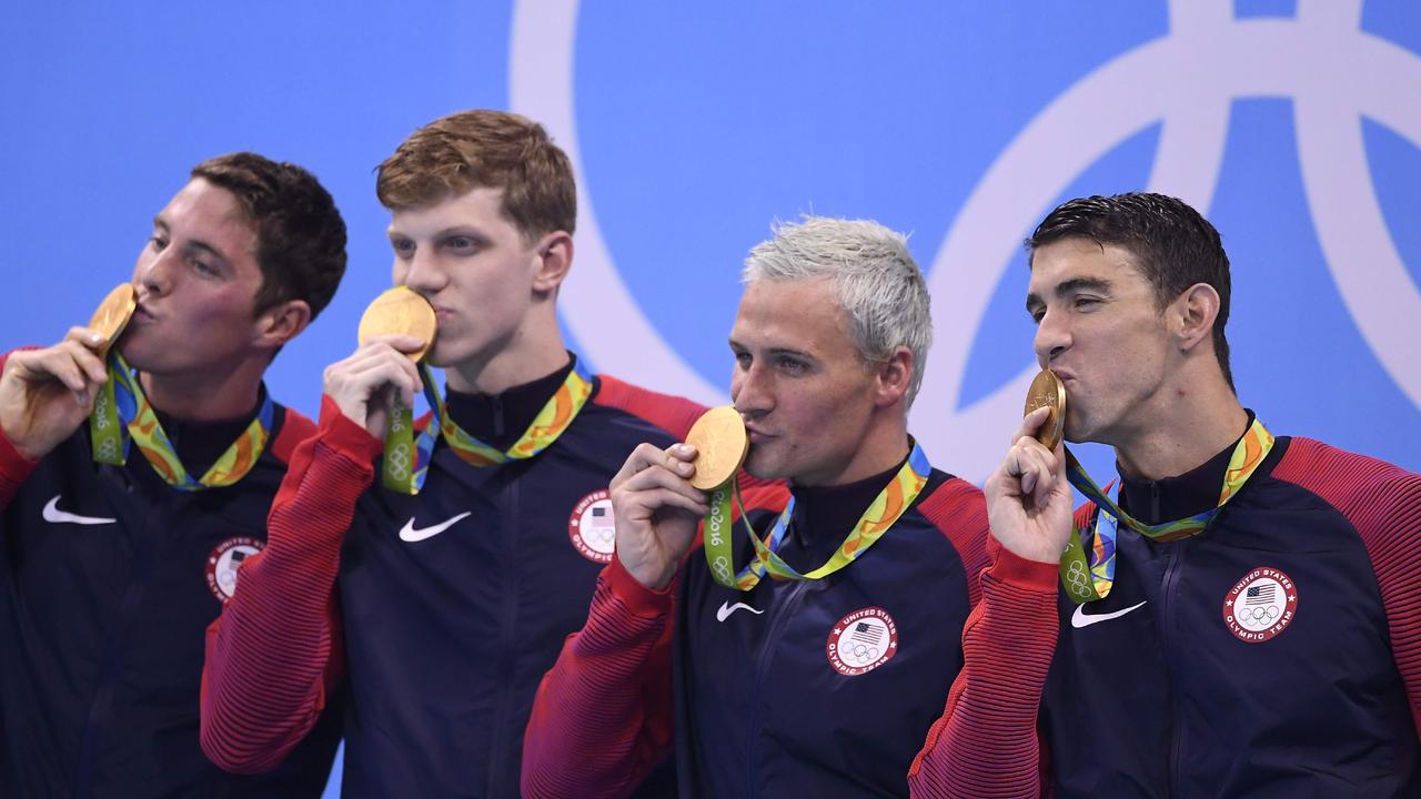 USA's Conor Dwyer, Townley Haas, Ryan Lochte (second from right) and Michael Phelps (far right) kiss their gold medals. AFP PHOTO / GABRIEL BOUYS.