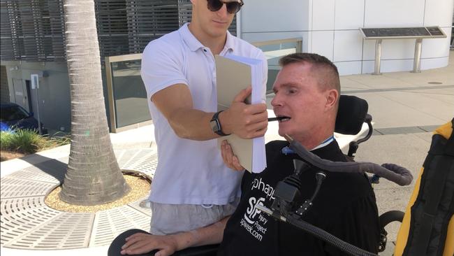 Gold Coast quadriplegic Perry Cross with Making Strides’ Daniel Boardman signs the ocean pools petition he championed.