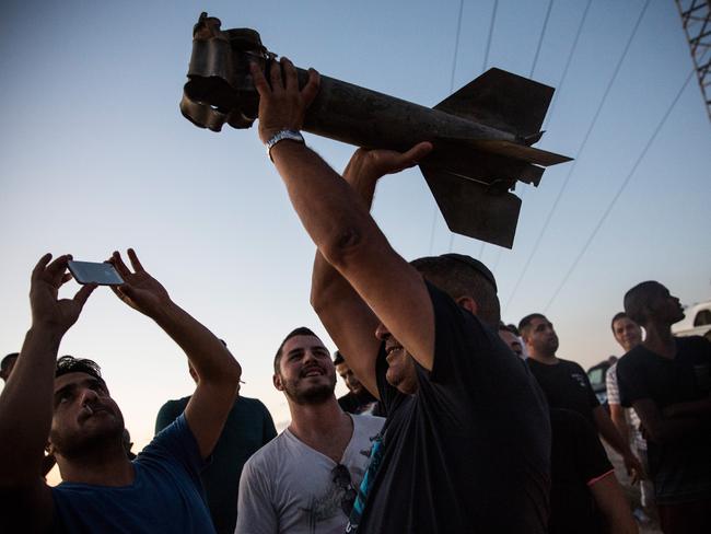 A man holds up a destroyed rocket, which he says was fired from inside Gaza towards Israel, for a crowd watching the Israeli attacks from Sderot. Picture: Andrew Burton/Getty Images