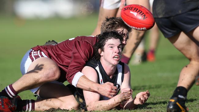 Adelaide University's Ben Adams gets a handball out despite pressure from PAOC’s Lachlan McNamara on Saturday. Picture: AAP/Dean Martin.