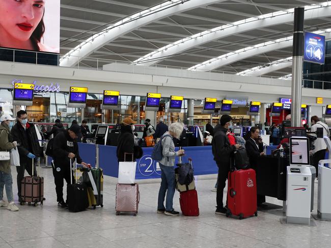 People queue at ticket machines at Heathrow Airport as travellers move to get home. Picture: AP