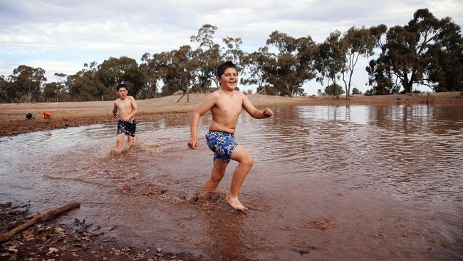 The farm dam’s water level is so low that James and Harrison can run through it. Picture: Sam Ruttyn