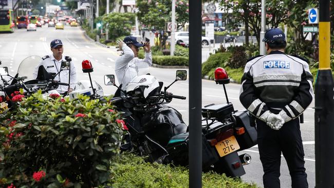 Police officers stand guard along the road outside the St. Regis Hotel, where Kim Jong-un is staying. Picture: AP.